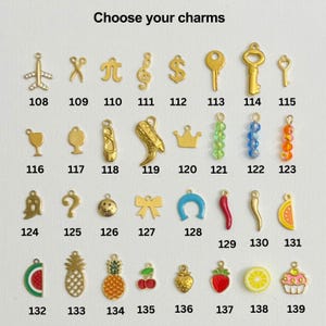 May include: A chart of gold charms with numbers 108 to 139. The charms include a variety of shapes, such as airplanes, keys, musical notes, crowns, and fruit. Choose your charms.