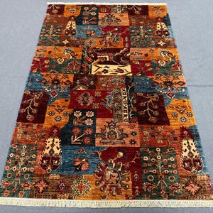 May include: A colourful area rug with a patchwork design featuring various shades of red, blue, and gold. The rug has a fringed border and intricate floral patterns.