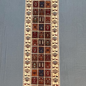 Pode incluir: Tapete retangular bege com um padrão repetitivo de quadrados em tons de vermelho, azul e laranja. O tapete tem uma borda com motivos florais e animais. Projetado para um corredor ou espaço estreito, com cerca de 200 cm de comprimento.