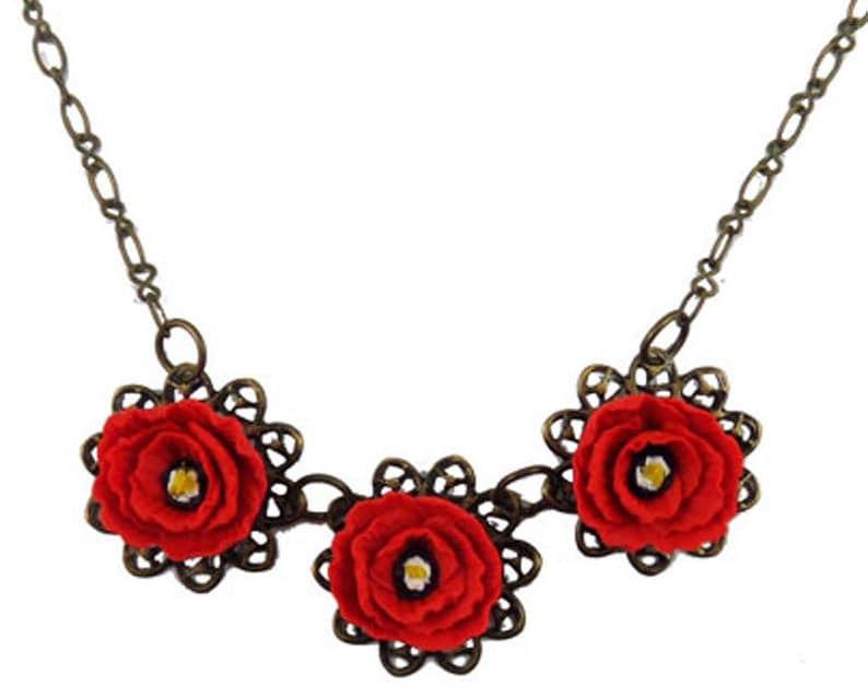 May include: A necklace with three red felt flowers on a bronze chain.