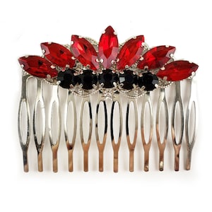 May include: A silver hair comb with a red and black crystal design. The comb has a row of red crystals in the shape of a crown, with black crystals surrounding the red crystals.