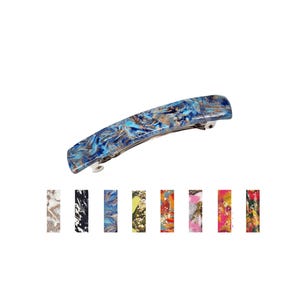 May include: A blue, gold, and white marbled hair barrette. The barrette is curved and has a metal clasp. Below are seven additional barrettes in various colors and patterns, including black, white, and gold.