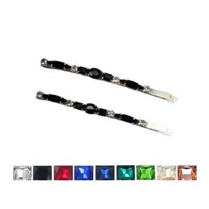 May include: Two silver hair clips with black oval-shaped rhinestones and clear round rhinestones.