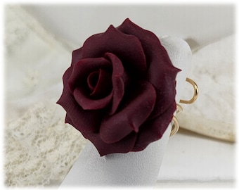 May include: A deep burgundy rose ring with a gold band. The rose is made of polymer clay and has a realistic appearance.