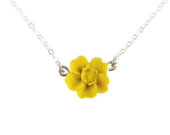 May include: A delicate silver chain necklace with a bright yellow flower pendant.