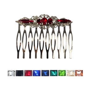 May include: A silver hair comb with a decorative design featuring red and clear rhinestones.