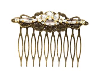 May include: A gold hair comb with a decorative design featuring clear rhinestones. The comb has 10 teeth.