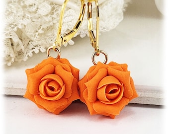 May include: A pair of orange rose earrings with gold leverback closures. The roses are made of polymer clay and have a realistic appearance.