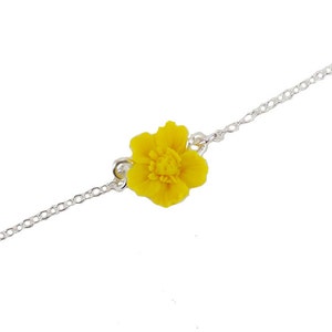 May include: A delicate silver chain necklace with a yellow flower charm.