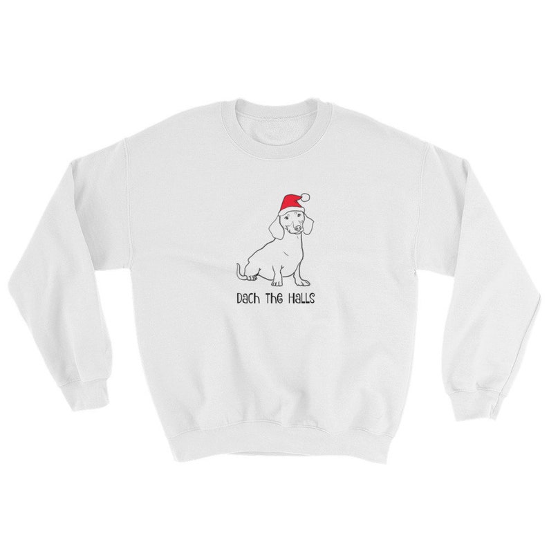 May include: White sweatshirt with a black and white illustration of a dachshund wearing a red Santa hat. The text "Dach the Halls" is printed below the dog.