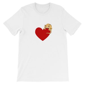 May include: White t-shirt with a red heart and a cartoon crested gecko on it.