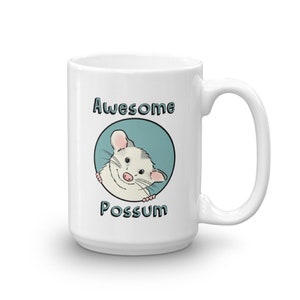 Puede incluir: Taza de cer&aacute;mica blanca con un c&iacute;rculo azul y un opossum de dibujos animados asom&aacute;ndose. El texto "Awesome Possum" est&aacute; impreso en la taza.