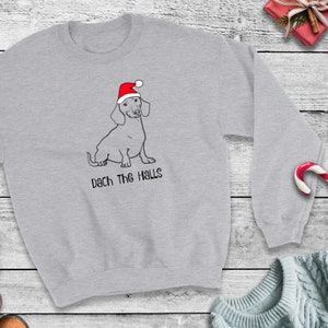 May include: A gray sweatshirt with a dachshund wearing a Santa hat and the text "Dach the Halls".