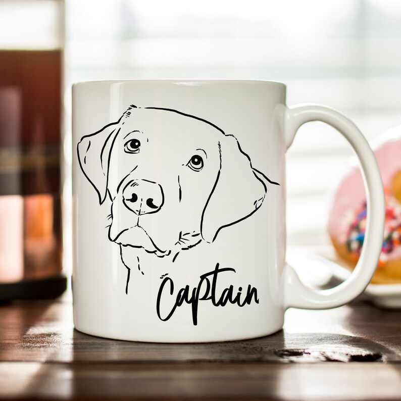 May include: White ceramic coffee mug with a black line drawing of a Labrador Retriever and the word "Captain" written in cursive.