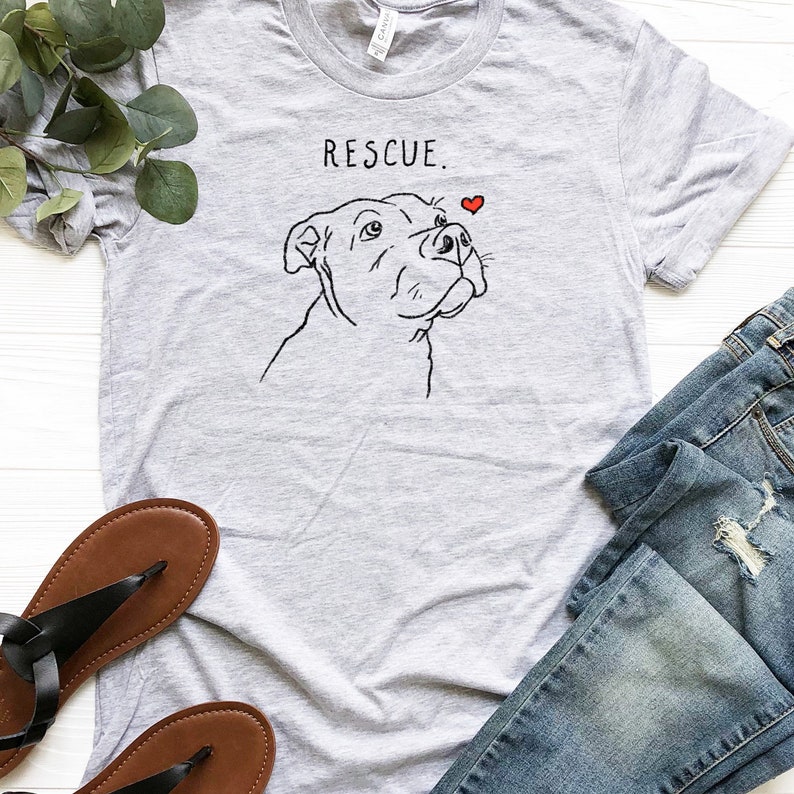 May include: Gray t-shirt with a black line drawing of a dog's head and the text "RESCUE." A small red heart is above the dog's head.