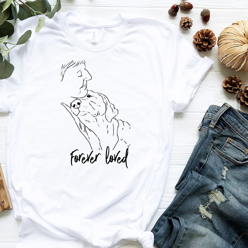 Puede incluir: Camiseta blanca con un dibujo en l&iacute;nea negra de una persona y un perro con el texto "Forever loved" debajo.