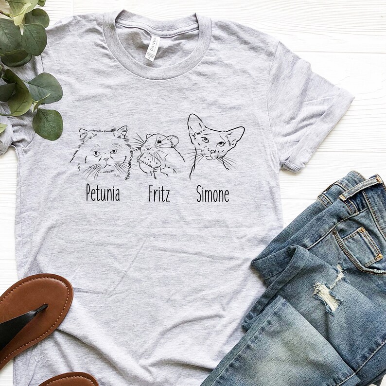 Puede incluir: Una camiseta gris con un dibujo en l&iacute;nea negra de tres mascotas: un gato, un h&aacute;mster y un gato. Las mascotas est&aacute;n etiquetadas como "Petunia", "Fritz" y "Simone".