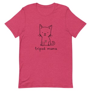 May include: A pink t-shirt with a black line drawing of a cat with a heart on its chest. The text "tripod mama" is printed below the cat.