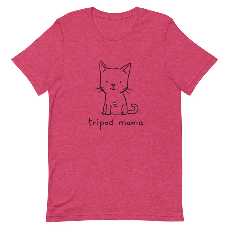 May include: A pink t-shirt with a black line drawing of a cat with a heart on its chest. The text "tripod mama" is printed below the cat.
