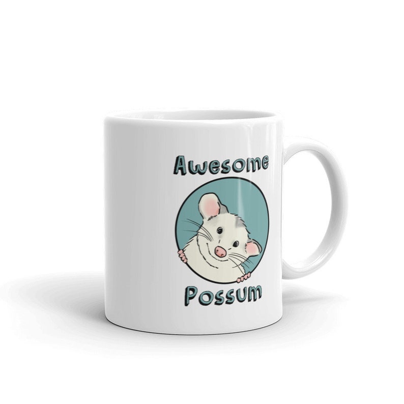 Puede incluir: Taza de cer&aacute;mica blanca con un c&iacute;rculo azul y un opossum de dibujos animados asom&aacute;ndose. El texto "Awesome Possum" est&aacute; impreso en la taza.