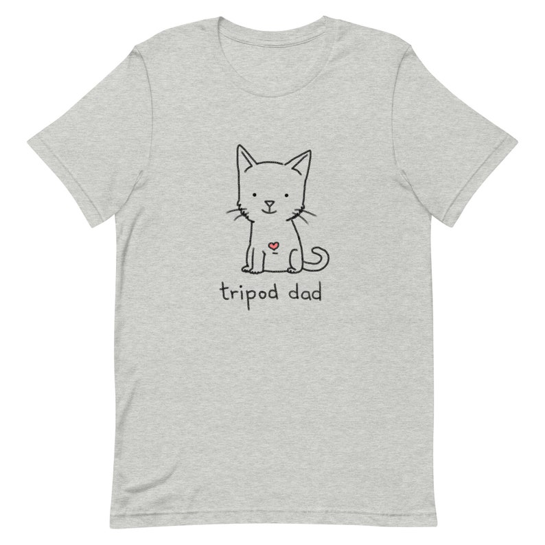 May include: A gray t-shirt with a black and white illustration of a cat with a red heart on its chest. The text "tripod dad" is printed below the cat.