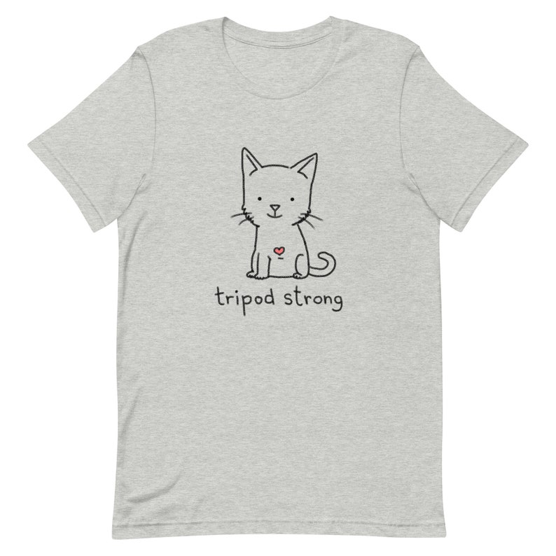May include: A gray t-shirt with a black and white illustration of a cat with a red heart on its chest. The text "tripod strong" is printed below the cat.
