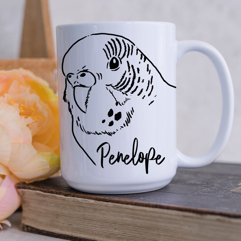 May include: White ceramic mug with a black and white illustration of a parakeet and the name "Penelope" printed on the front.