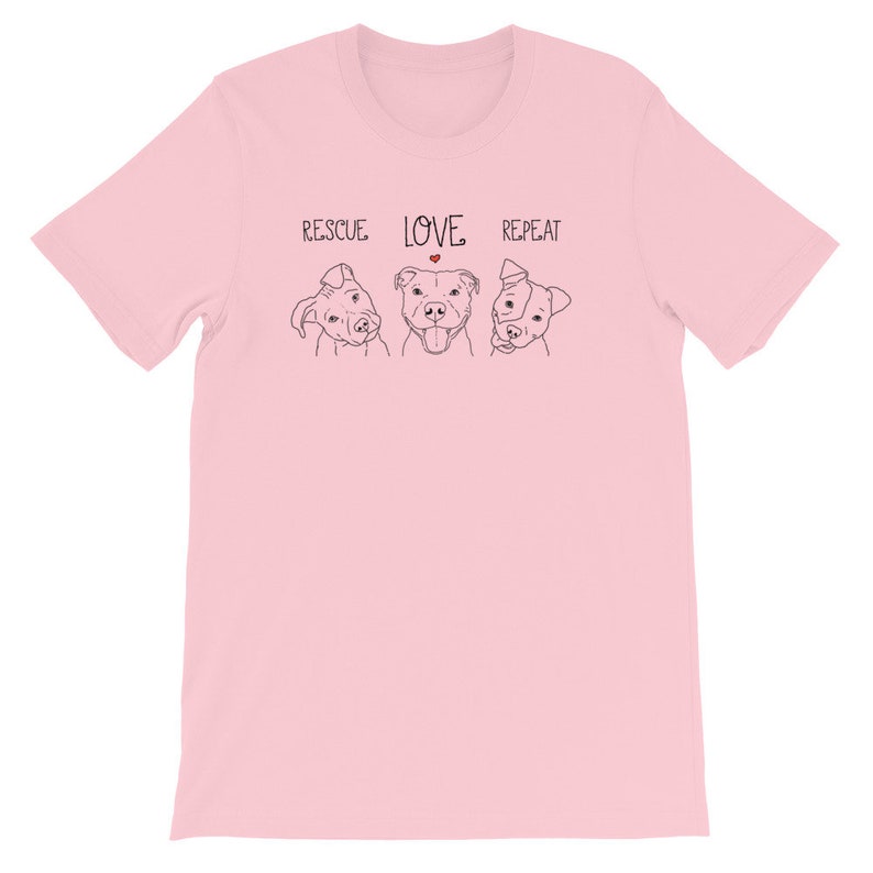 Puede incluir: Camiseta rosa con un dibujo en l&iacute;nea negra de tres perros y el texto "RESCUE LOVE REPEAT" con un coraz&oacute;n rojo sobre la palabra "LOVE".