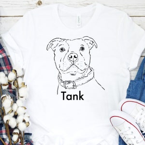 Puede incluir: Camiseta blanca con un dibujo de l&iacute;nea negra de la cabeza de un perro y el nombre "Tank" impreso debajo.