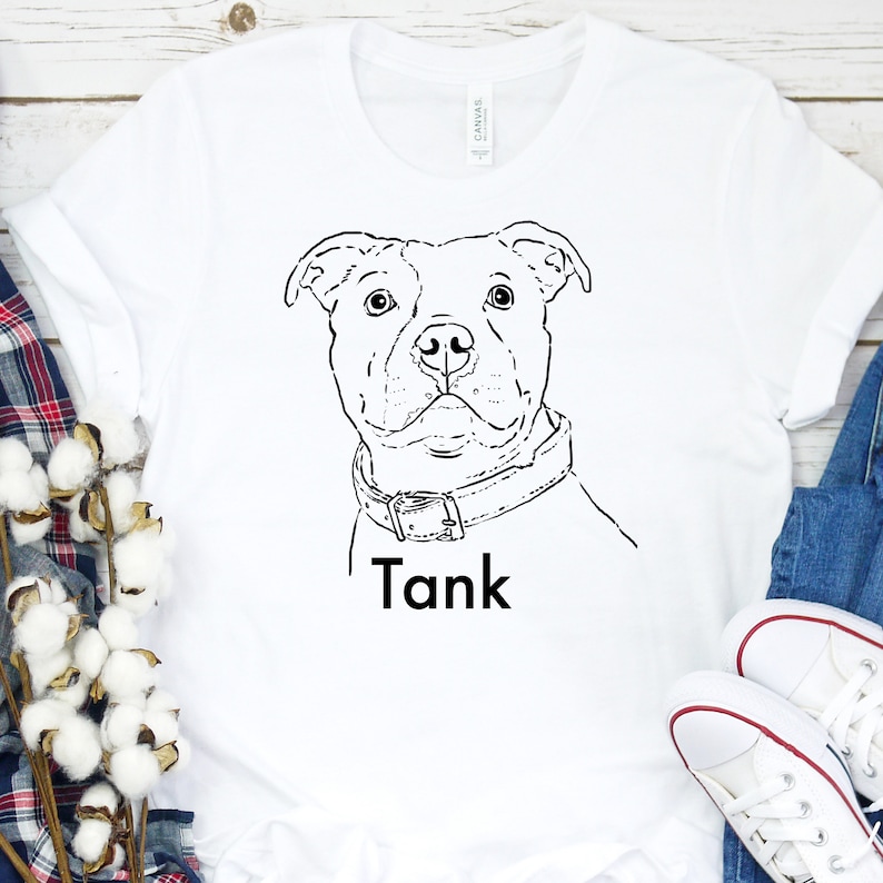 Puede incluir: Camiseta blanca con un dibujo de l&iacute;nea negra de la cabeza de un perro y el nombre "Tank" impreso debajo.