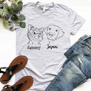 Puede incluir: Una camiseta gris con un dibujo en l&iacute;nea negra de dos perros. El perro de la izquierda es un Yorkshire Terrier y est&aacute; etiquetado como "Sammy". El perro de la derecha es un Labrador Retriever y est&aacute; etiquetado como "Jasmine".