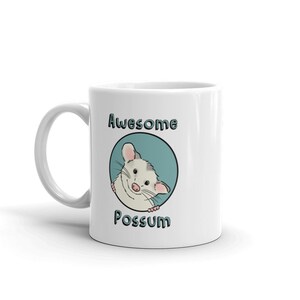 Puede incluir: Taza de cer&aacute;mica blanca con un c&iacute;rculo azul y un opossum de dibujos animados asom&aacute;ndose. El texto "Awesome Possum" est&aacute; impreso en la taza.