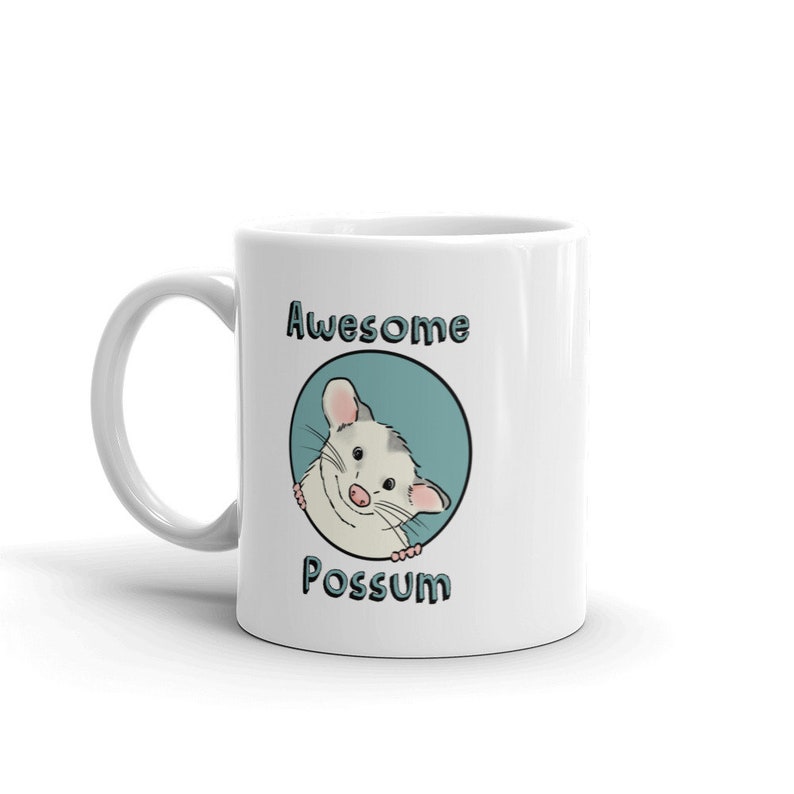 Puede incluir: Taza de cer&aacute;mica blanca con un c&iacute;rculo azul y un opossum de dibujos animados asom&aacute;ndose. El texto "Awesome Possum" est&aacute; impreso en la taza.