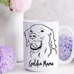 May include: White ceramic mug with a black line drawing of a Golden Retriever dog with its mouth open and a ball in its mouth. The text "Golden Mama" is printed in black at the bottom of the mug.