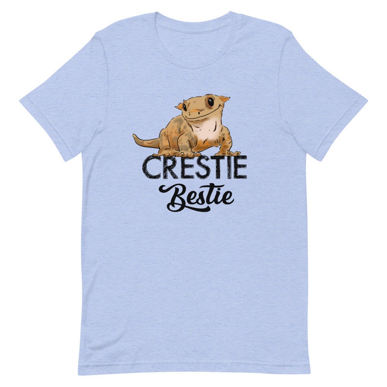 May include: Light blue t-shirt with a cartoon crested gecko and the text "Crestiebestie" in black.