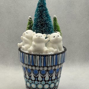 May include: A decorative flower pot with a winter theme. The pot is painted with blue and white patterns and contains three white polar bear figurines and miniature green and blue Christmas trees. The text "Option 1" is in the upper right corner.
