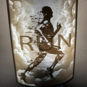 Pode incluir: Uma luz noturna branca com uma silhueta de uma pessoa correndo através de nuvens. A palavra "RUN" está impressa na imagem.