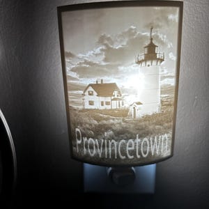Może przedstawiać: Biała ceramiczna lampka nocna z sepią fotografią latarni morskiej i domu z napisem "Provincetown" pod obrazem.