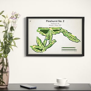 May include: A black framed print of a golf course map titled "Pinehurst No. 2" with the text "Pinehurst, NC Donald J. Ross, 1907". The map shows the layout of the golf course with green and yellow lines.
