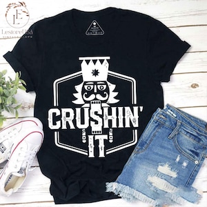 May include: Black t-shirt featuring a white graphic of a nutcracker with the text "Crushin' It".