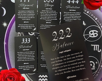 May include: A collection of black oracle cards with white text, featuring numbers and words like "Alignment," "Change," and "Balance." The cards are arranged on a purple and white patterned surface, with red roses in the corners.