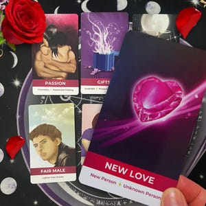May include: A selection of tarot cards featuring illustrations and text. One card displays "NEW LOVE" with a pink heart. Other cards show images of embracing figures, a gift box, and a man. A red rose and petals are scattered around the cards.