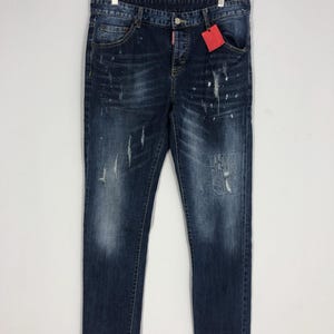 Könnte beinhalten: Blaue Jeans aus Denim mit Destroyed-Effekten, Farbspritzern und Rissen. Die Jeans haben einen klassischen Fünf-Taschen-Stil und eine gerade Beinpartie.