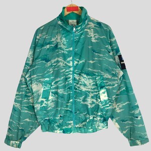 May include: A teal blue jacket with a white wave pattern. The jacket has a zipper closure and a stand-up collar.