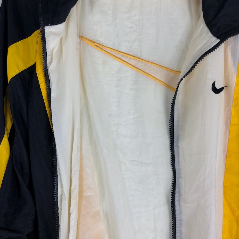 May include: Black and yellow windbreaker jacket with a zipper closure and a white lining. The jacket has a Nike logo on the right side.