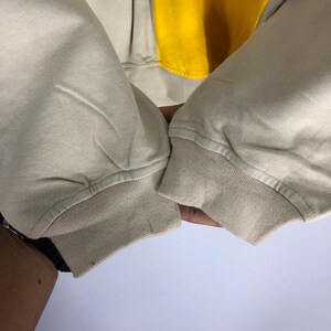 May include: Close-up of the beige coloured cuffs of a sweatshirt. The cuffs are folded over and have a ribbed texture.