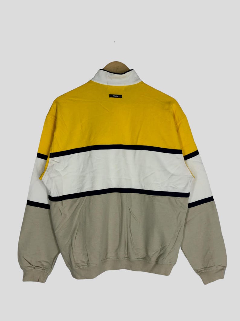 May include: A yellow, white and beige striped long-sleeved sweatshirt with a black zip and a small "P.L.A." logo on the back.