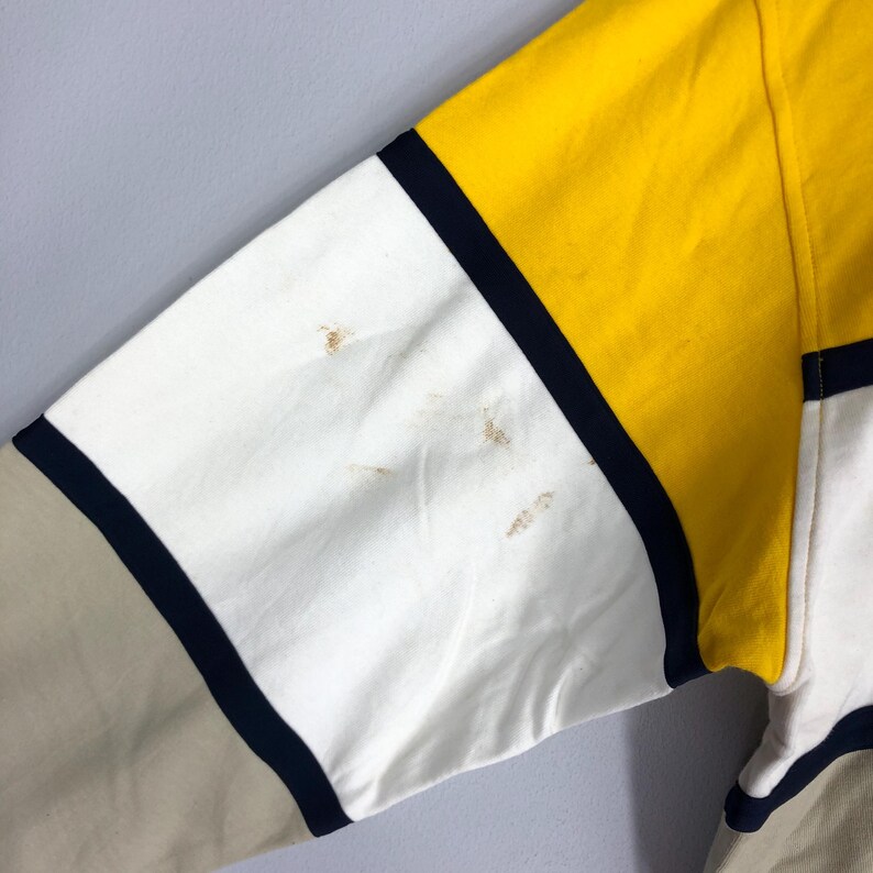 May include: A multi-coloured striped long-sleeved shirt with yellow, white, beige and navy blue stripes.