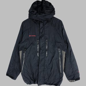 Puede incluir: Una chaqueta negra con capucha Columbia con un logotipo rojo y bolsillos con cremallera.