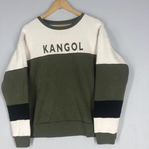 Może przedstawiać: Zestaw trzech ceramicznych kubk&oacute;w z nakrapianą, kremową glazurą. Każdy kubek ma inny ręcznie malowany kwiatowy wz&oacute;r w odcieniach niebieskiego, zielonego i ż&oacute;łtego. Kubki mają prosty, zaokrąglony kształt i wygodny uchwyt.